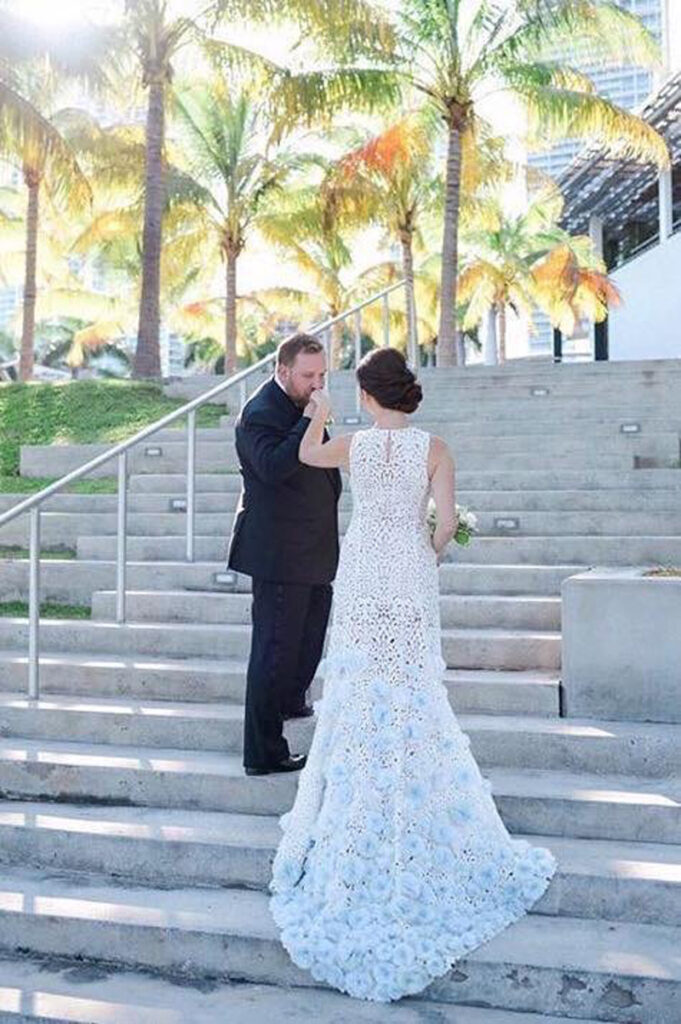 Spectacular hand detailed gown of lace and blue flowers - Bride and Groom on the steps in their destination event in the tropics